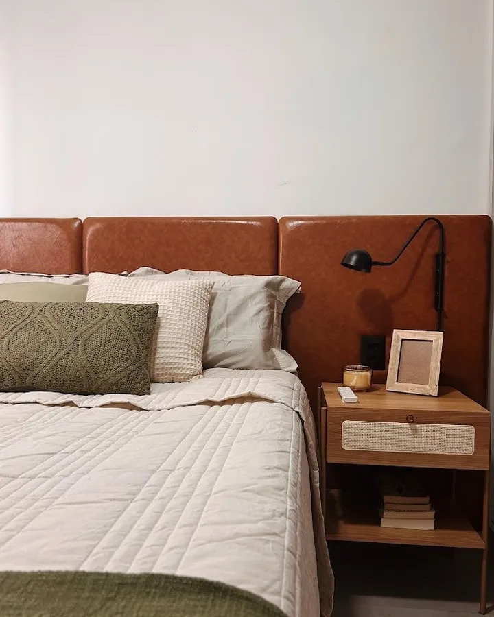 Dormitório 1209: cabeceira de couro caramelo, roupa de cama clara e almofadas verde-oliva