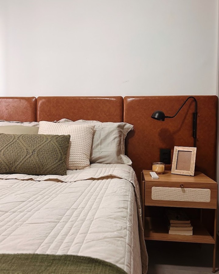 Dormitório 1209: cabeceira de couro caramelo, roupa de cama clara e almofadas verde-oliva
